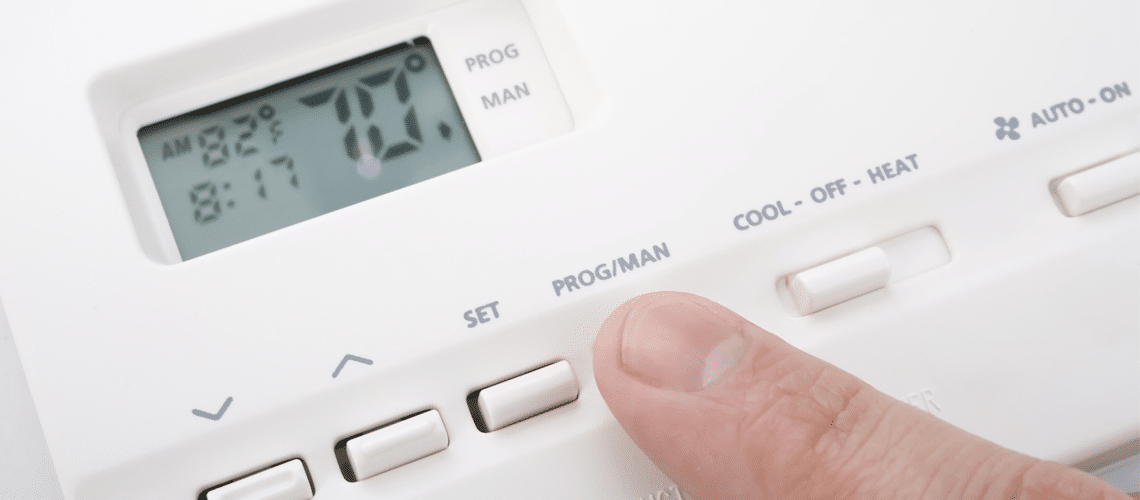 a finger pressing a button of a thermostat Air conditioner repair