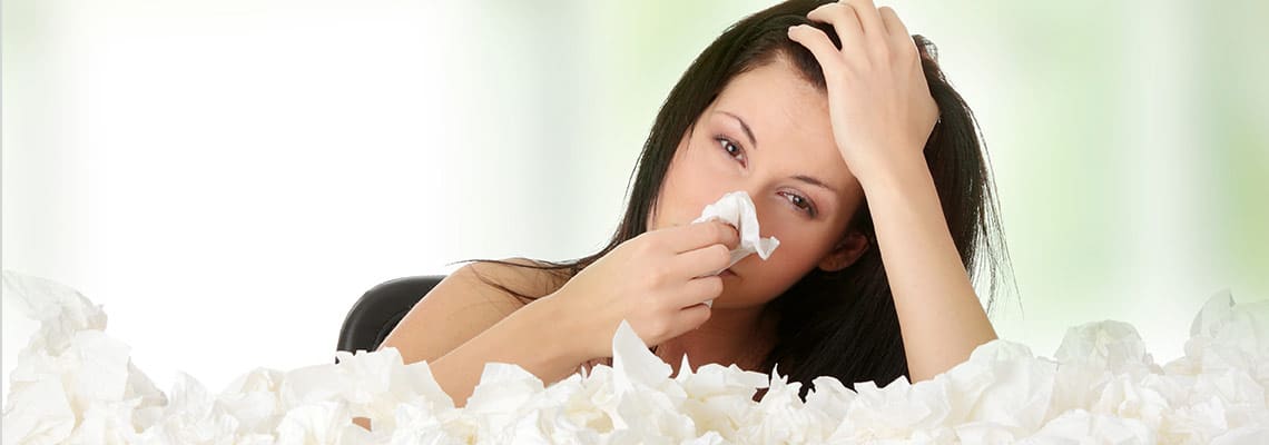 woman blowing nose from allergies