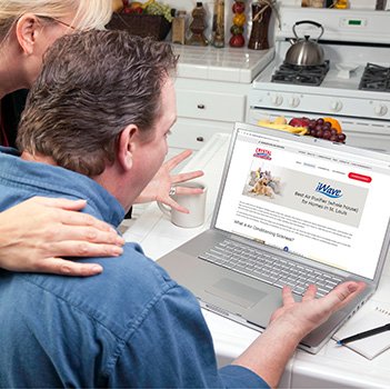 Couple In Kitchen Using Laptop to Research Travel, Vacations or Real Estate. Screen can be easily used for your own message or picture. Picture on screen is my copyright as well.